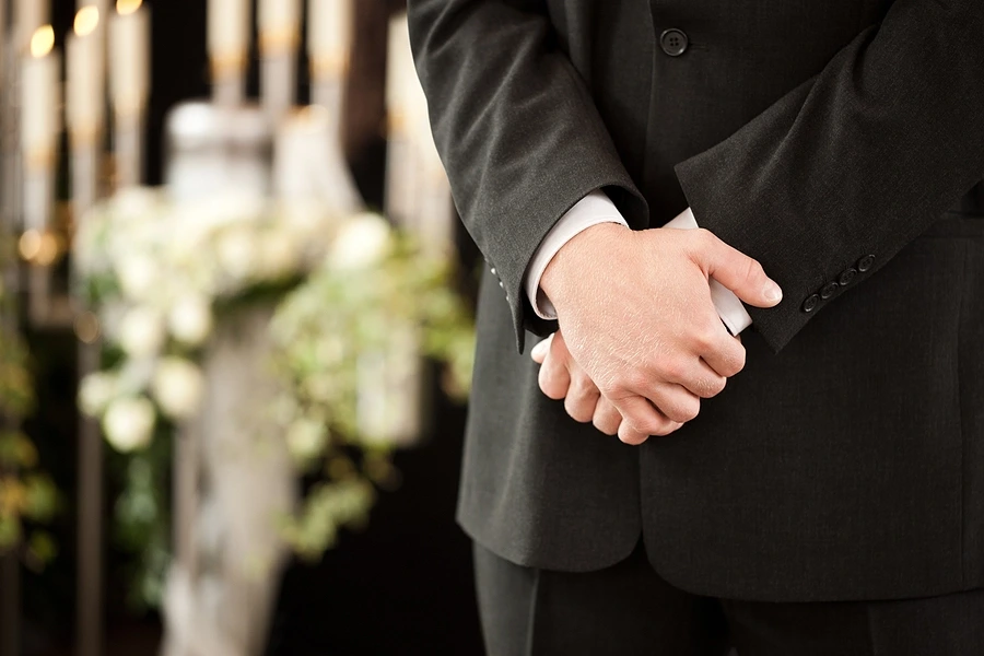 Close up of folded hands at furneral service